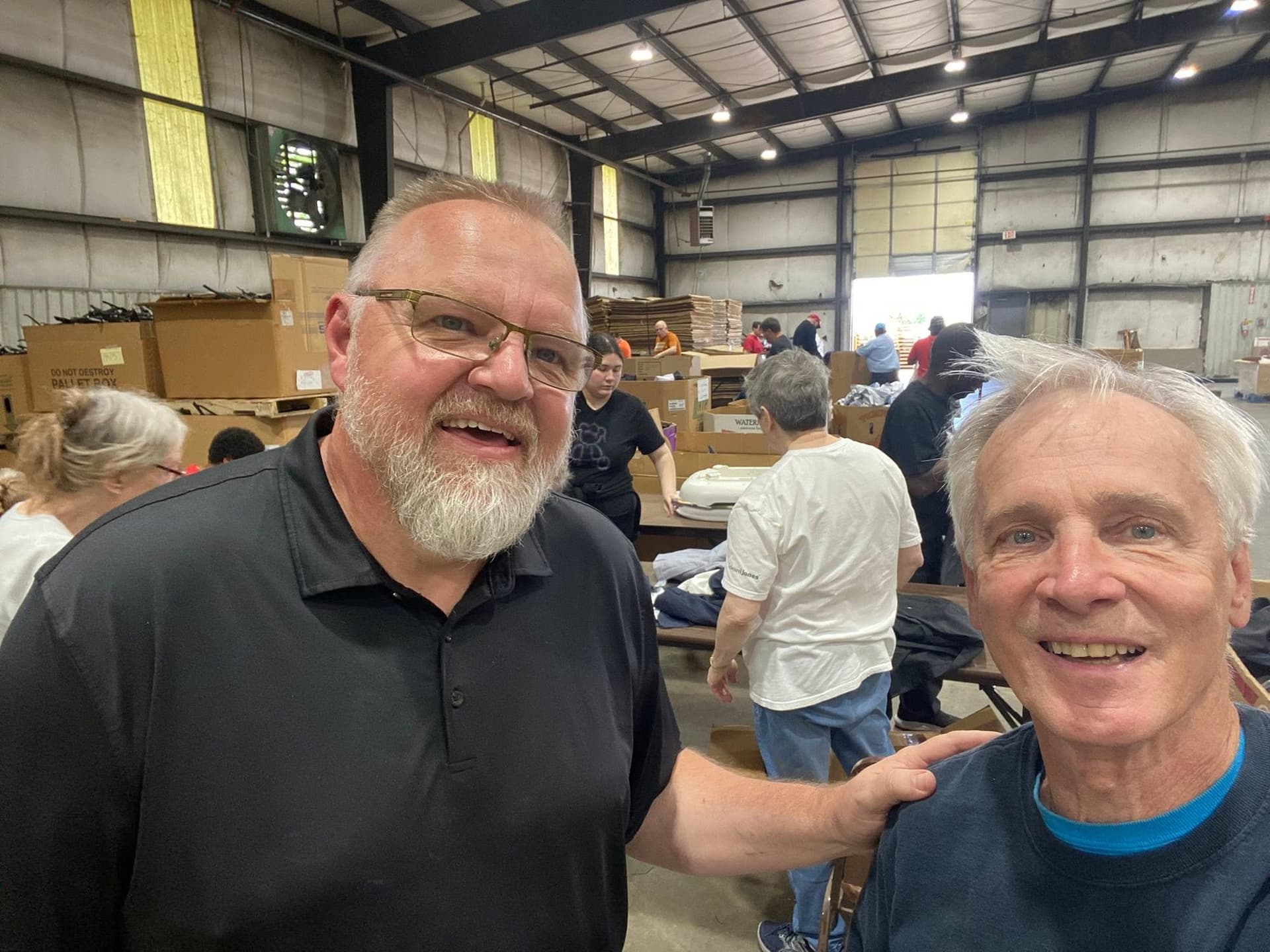 John Armbruster with a volunteer organizer at a warehouse where people are sorting donated goods.
